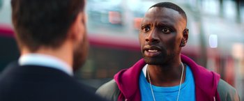 Movie still from “The Takedown” (2022), directed by Louis Leterrier – A man talking to another man in front of a building; Close Up shot, Over the shoulder angle