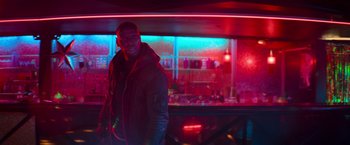 Movie still from “The Takedown” (2022), directed by Louis Leterrier – A man standing in front of a bar at night; Medium shot, Low angle