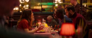 Movie still from “The Takedown” (2022), directed by Louis Leterrier – A man and a woman sitting at a dinner table; Medium shot, Over the shoulder angle