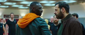Movie still from “The Takedown” (2022), directed by Louis Leterrier – Two men talking to each other in a room; Medium shot, Over the shoulder angle