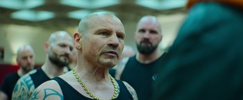 Movie still from “The Takedown” (2022), directed by Louis Leterrier – A man with a bald head is looking at the camera while a man with a bald head is looking at the camera; Close Up shot, Over the shoulder angle