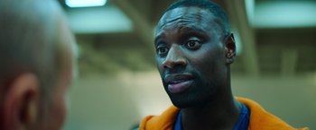 Movie still from “The Takedown” (2022), directed by Louis Leterrier – A person looking at the camera; Close Up shot, Over the shoulder angle
