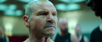 Movie still from “The Takedown” (2022), directed by Louis Leterrier – An older man with a beard and mustache; Close Up shot, Low angle