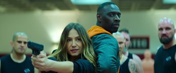Movie still from “The Takedown” (2022), directed by Louis Leterrier – A man and a woman posing for a picture; Close Up shot, Over the shoulder angle