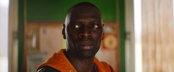 Movie still from “The Takedown” (2022), directed by Louis Leterrier – A person wearing an orange jacket; Close Up shot, High angle