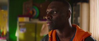 Movie still from “The Takedown” (2022), directed by Louis Leterrier – A person wearing a jacket looking to his left; Close Up shot, Over the shoulder angle