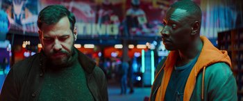 Movie still from “The Takedown” (2022), directed by Louis Leterrier – Two men standing next to each other on a city street; Medium shot, Over the shoulder angle
