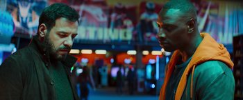 Movie still from “The Takedown” (2022), directed by Louis Leterrier – Two men standing next to each other on a city street; Medium shot, Low angle