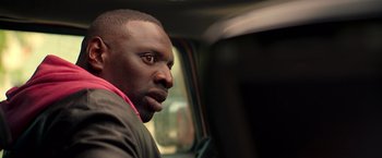 Movie still from “The Takedown” (2022), directed by Louis Leterrier – A person sitting in a car; Close Up shot, Over the shoulder angle