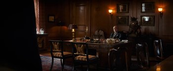 Movie still from “The Trial of the Chicago 7” (2020), directed by Aaron Sorkin – A man sitting at a desk in front of a lamp; Wide shot, Low angle