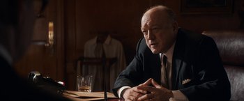 Movie still from “The Trial of the Chicago 7” (2020), directed by Aaron Sorkin – An older man sitting at a table in front of a glass of water; Medium shot, Over the shoulder angle