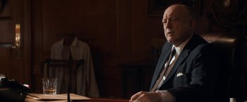 Movie still from “The Trial of the Chicago 7” (2020), directed by Aaron Sorkin – An older man sitting at a table in a suit; Medium shot, Over the shoulder angle