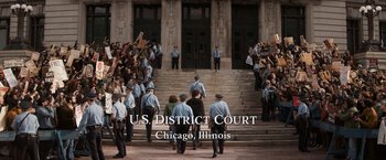 Movie still from “The Trial of the Chicago 7” (2020), directed by Aaron Sorkin – A group of people are walking down the steps of a courthouse; Extreme Wide shot, High angle