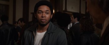 Movie still from “The Trial of the Chicago 7” (2020), directed by Aaron Sorkin – A man with a beard is standing in a room; Close Up shot, Over the shoulder angle