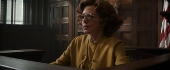 Movie still from “The Trial of the Chicago 7” (2020), directed by Aaron Sorkin – An older woman wearing glasses and a yellow jacket; Medium shot, Low angle