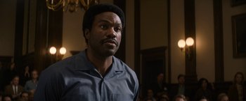 Movie still from “The Trial of the Chicago 7” (2020), directed by Aaron Sorkin – A man in a blue shirt is looking to his left; Close Up shot, Over the shoulder angle