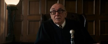 Movie still from “The Trial of the Chicago 7” (2020), directed by Aaron Sorkin – An older man in a judge's robe sitting in a chair; Close Up shot, Over the shoulder angle