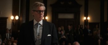 Movie still from “The Trial of the Chicago 7” (2020), directed by Aaron Sorkin – A man in a suit and tie standing in front of a group of people; Close Up shot, Over the shoulder angle