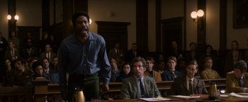 Movie still from “The Trial of the Chicago 7” (2020), directed by Aaron Sorkin – A man standing in front of a group of people in a courtroom; Medium shot, Low angle