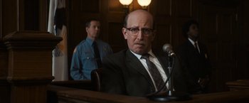 Movie still from “The Trial of the Chicago 7” (2020), directed by Aaron Sorkin – A man sitting in front of a microphone in front of a judge; Close Up shot, Over the shoulder angle