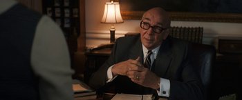 Movie still from “The Trial of the Chicago 7” (2020), directed by Aaron Sorkin – An older man wearing a suit and tie sitting at a desk; Medium shot, Over the shoulder angle