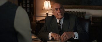 Movie still from “The Trial of the Chicago 7” (2020), directed by Aaron Sorkin – An older man sitting at a desk in a suit; Close Up shot, Over the shoulder angle