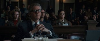 Movie still from “The Trial of the Chicago 7” (2020), directed by Aaron Sorkin – A man sitting in front of a group of people in a courtroom; Medium shot, Over the shoulder angle