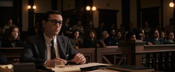 Movie still from “The Trial of the Chicago 7” (2020), directed by Aaron Sorkin – A man sitting in front of a group of people in a courtroom; Medium shot, Low angle