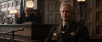 Movie still from “The Trial of the Chicago 7” (2020), directed by Aaron Sorkin – A police officer sitting in front of a mirror in a room; Medium shot, Over the shoulder angle