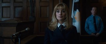 Movie still from “The Trial of the Chicago 7” (2020), directed by Aaron Sorkin – A woman wearing a suit and tie in front of a wooden wall; Close Up shot, Low angle