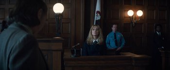 Movie still from “The Trial of the Chicago 7” (2020), directed by Aaron Sorkin – A woman sitting at a table in front of a microphone in a courtroom; Medium shot, Low angle