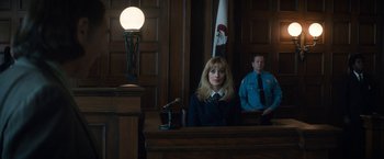 Movie still from “The Trial of the Chicago 7” (2020), directed by Aaron Sorkin – A woman sitting at a table in front of a microphone in a courtroom; Medium shot, Low angle