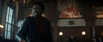 Movie still from “The Trial of the Chicago 7” (2020), directed by Aaron Sorkin – A man standing in front of a wall with lights on; Medium shot, Low angle