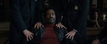 Movie still from “The Trial of the Chicago 7” (2020), directed by Aaron Sorkin – A man in a red shirt and a leather jacket; Medium shot, High angle