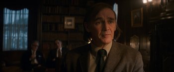 Movie still from “The Trial of the Chicago 7” (2020), directed by Aaron Sorkin – A man in a suit and tie in front of a book shelf; Medium shot, Over the shoulder angle