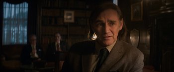 Movie still from “The Trial of the Chicago 7” (2020), directed by Aaron Sorkin – A man in a suit and tie in front of a book shelf; Close Up shot, Over the shoulder angle