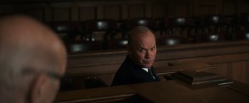 Movie still from “The Trial of the Chicago 7” (2020), directed by Aaron Sorkin – A man sitting in front of a bunch of chairs in a room; Medium shot, Over the shoulder angle