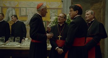 Movie still from “The Two Popes” (2019), directed by Fernando Meirelles – A group of three men standing next to each other; Medium shot, Over the shoulder angle