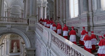 Movie still from “The Two Popes” (2019), directed by Fernando Meirelles – A group of men in red and white robes standing on a staircase; Extreme Wide shot, High angle