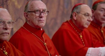 Movie still from “The Two Popes” (2019), directed by Fernando Meirelles – Two men in red robes are standing next to each other; Close Up shot, Over the shoulder angle