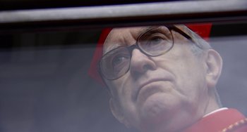 Movie still from “The Two Popes” (2019), directed by Fernando Meirelles – An old man wearing glasses looking out a window; Close Up shot, Low angle