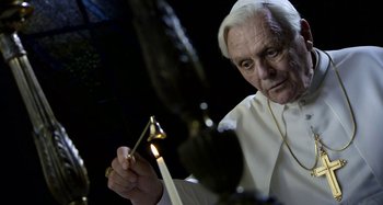 Movie still from “The Two Popes” (2019), directed by Fernando Meirelles – An old man in a priest's outfit lighting a candle; Close Up shot, Over the shoulder angle