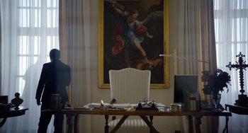 Movie still from “The Two Popes” (2019), directed by Fernando Meirelles – A white chair sitting in front of a painting on the wall; Wide shot, Low angle