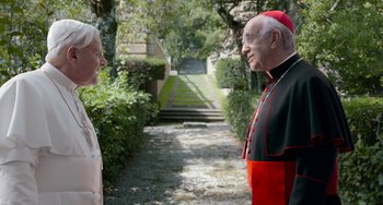 Movie still from “The Two Popes” (2019), directed by Fernando Meirelles – A man and a woman are talking in a garden; Medium shot, High angle