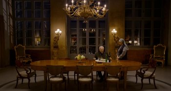 Movie still from “The Two Popes” (2019), directed by Fernando Meirelles – Two people are sitting at a long wooden dining table; Wide shot, High angle