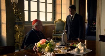 Movie still from “The Two Popes” (2019), directed by Fernando Meirelles – Two men in suits are sitting at a dinner table; Medium shot, Over the shoulder angle