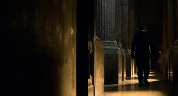 Movie still from “The Two Popes” (2019), directed by Fernando Meirelles – A person walking in a hallway with pillars; Extreme Wide shot, Low angle
