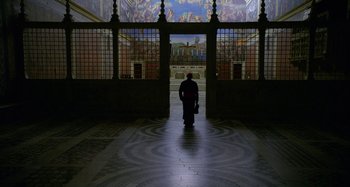 Movie still from “The Two Popes” (2019), directed by Fernando Meirelles – A person is standing in a room with a suitcase; Extreme Wide shot, High angle