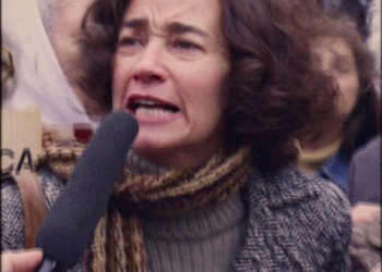 Movie still from “The Two Popes” (2019), directed by Fernando Meirelles – A woman with a microphone in her mouth; Close Up shot, High angle