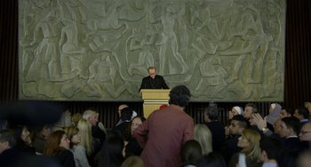 Movie still from “The Two Popes” (2019), directed by Fernando Meirelles – A man is giving a speech in front of an audience; Wide shot, High angle